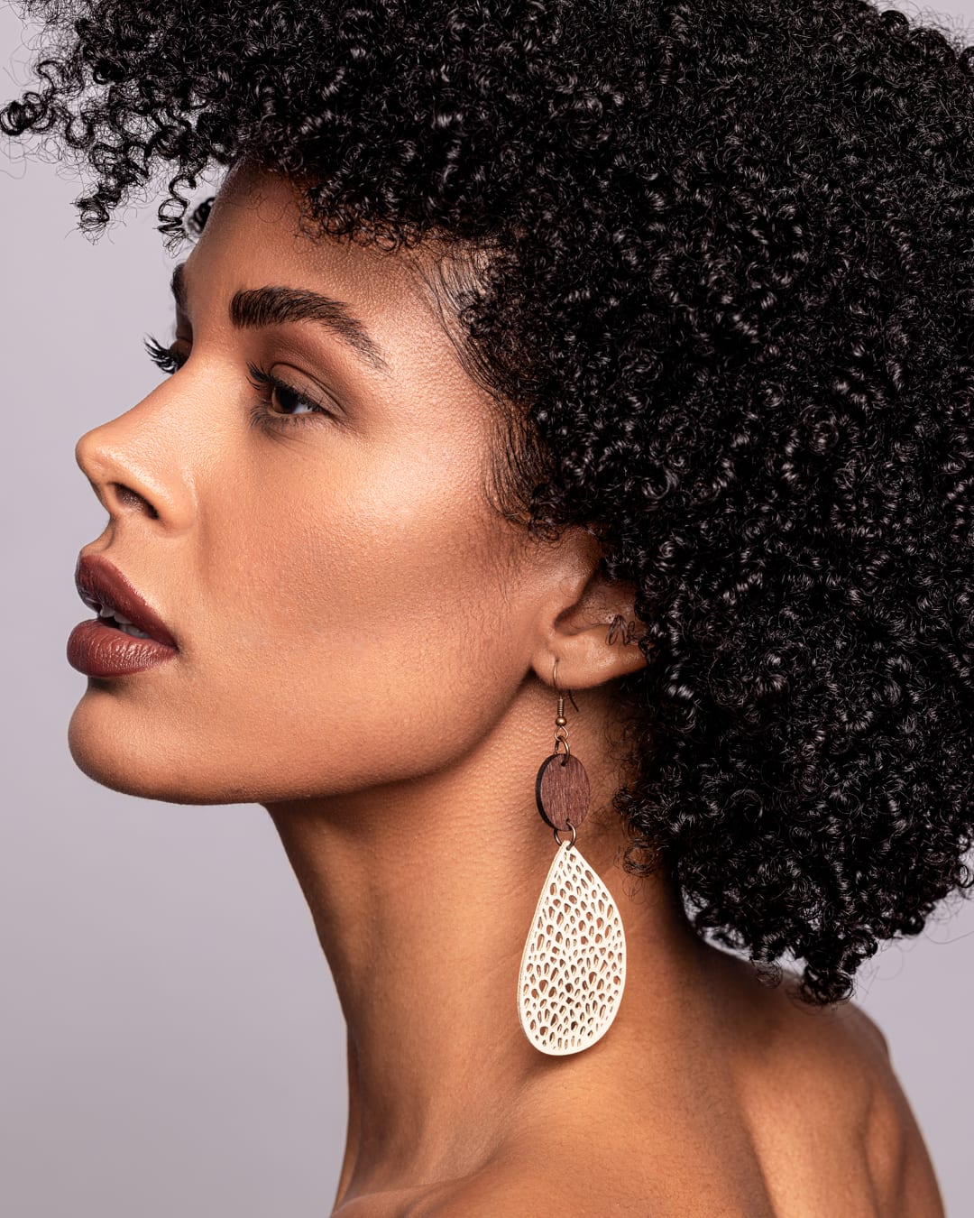 Beauty-Profil eines Models mit Afro und großem goldfarbenem Ohrring