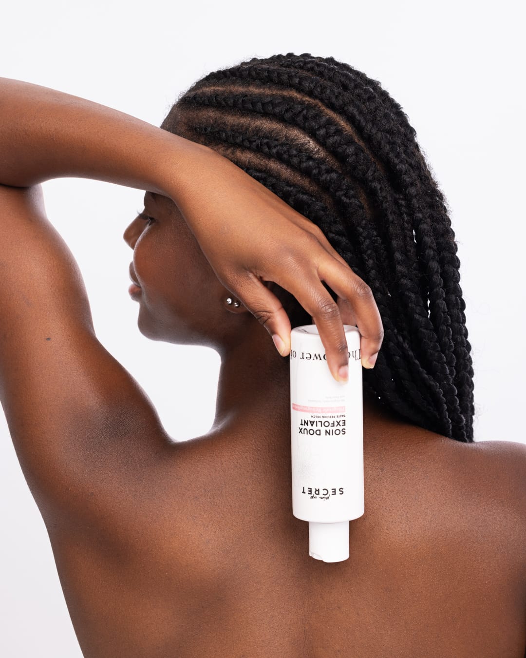 Skincare-Aufnahme eines Models mit geflochtenem Haar und weißer Produktflasche